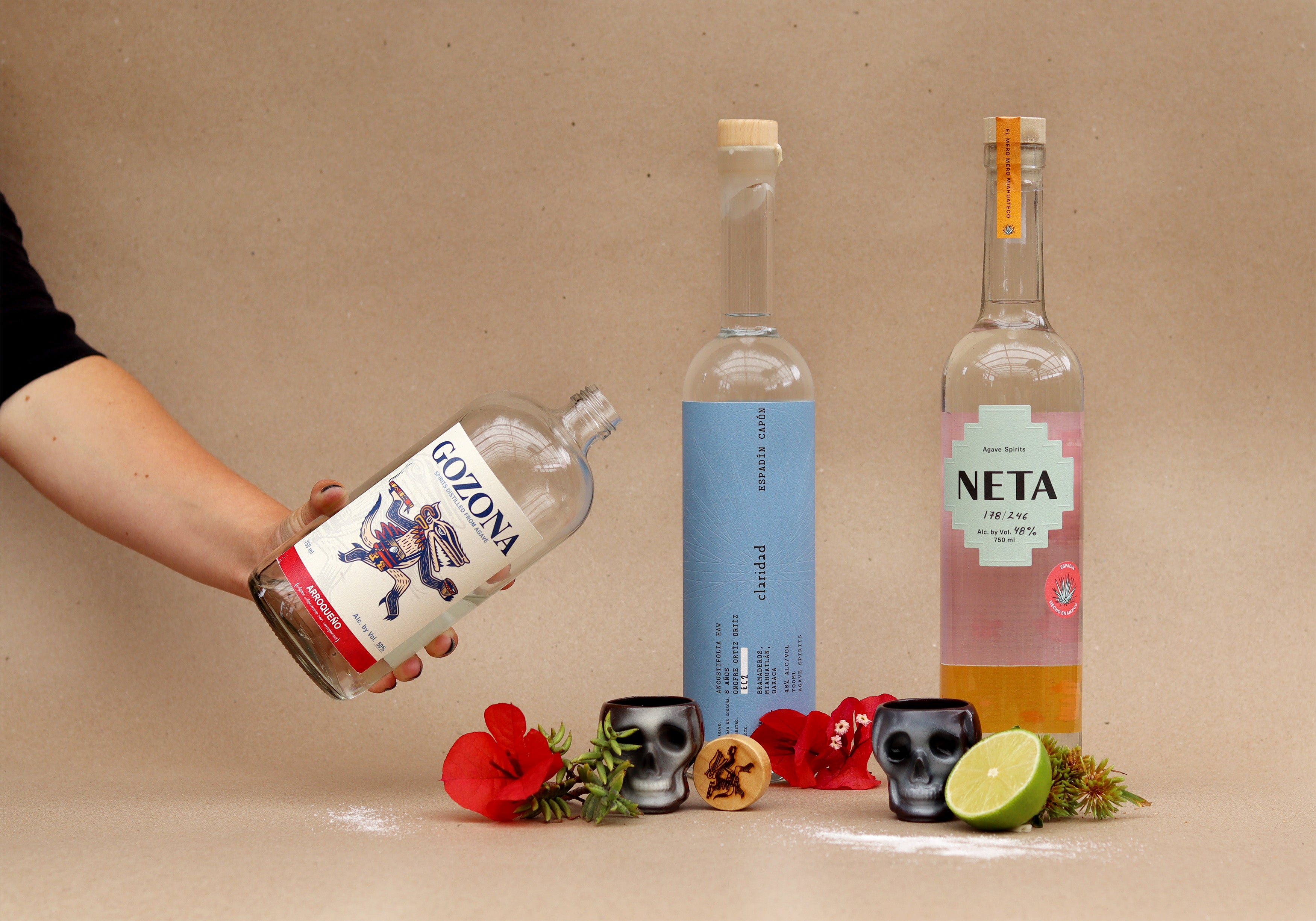 Three bottles of mezcal with colorful labels on a beige background