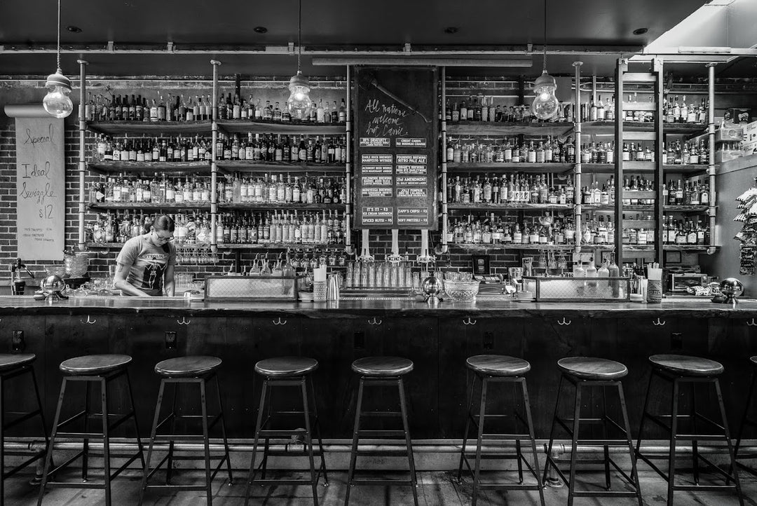 Black and white image of the Prizefighter bar with a bartender standing behind it