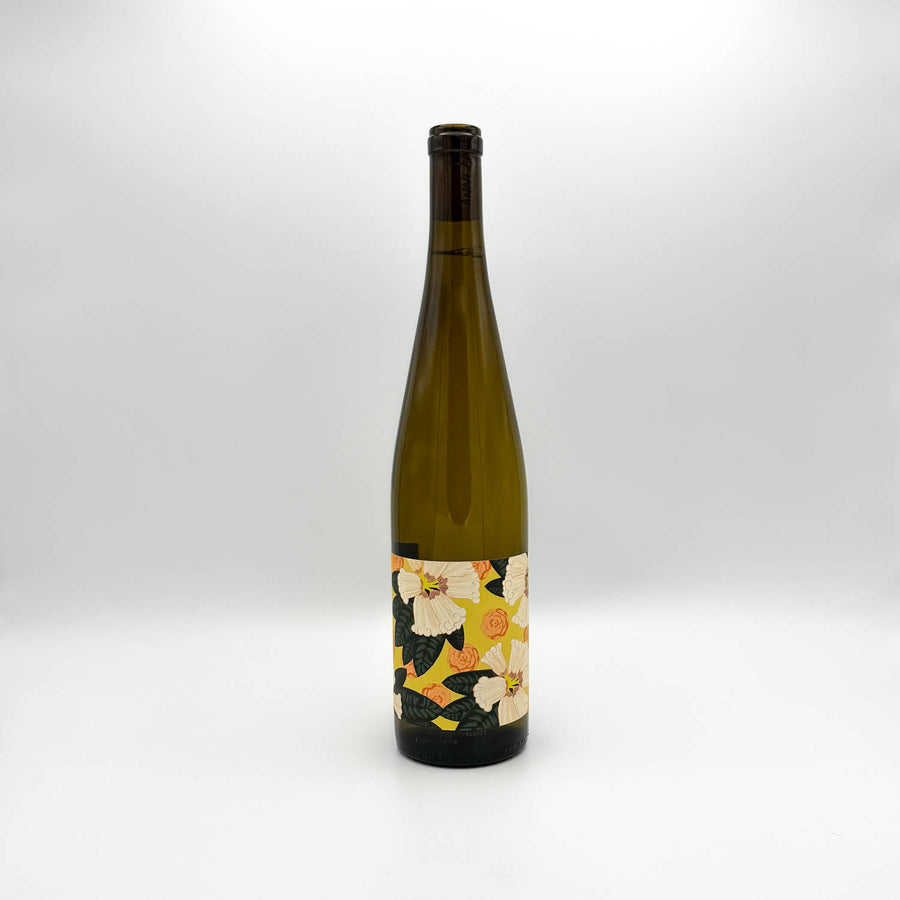 A tall, dark green glass bottle with a colorful floral label, standing upright on a light gray background.