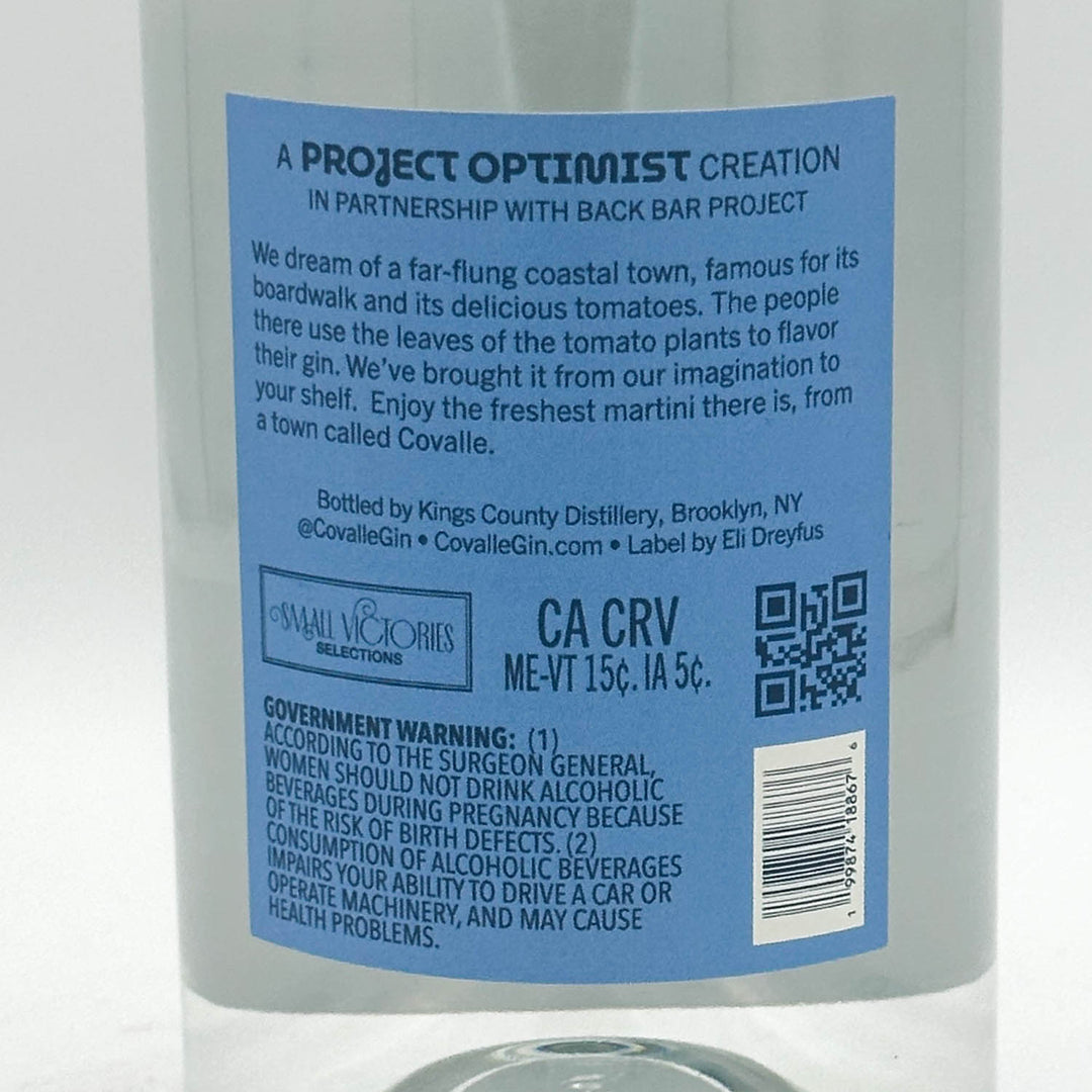 A clear glass bottle of CovalleTomato-Water Gin with a vintage-style blue label, photographed against a neutral light gray background.