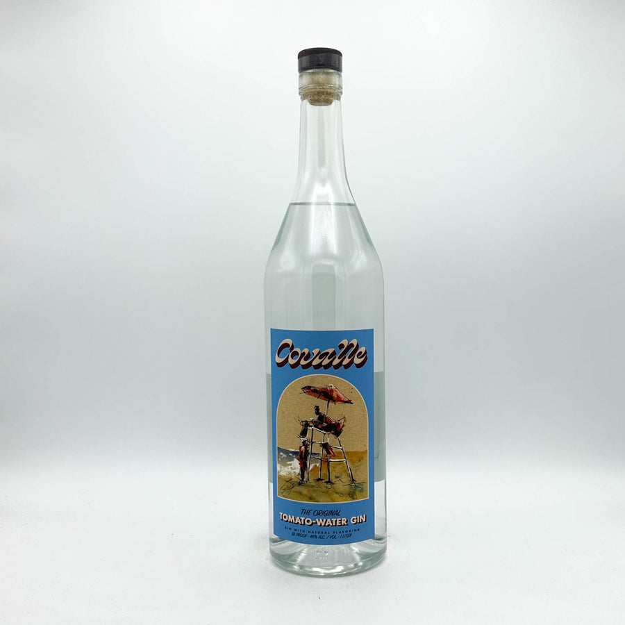 A clear glass bottle of CovalleTomato-Water Gin with a vintage-style blue label, photographed against a neutral light gray background.