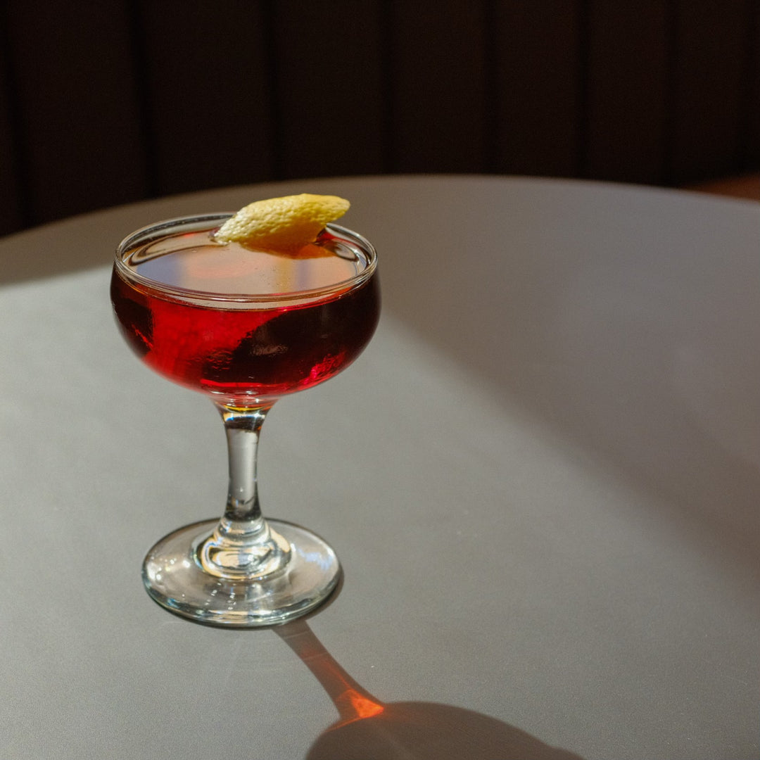 The Reconquista cocktail in a coupe glass with a lemon peel garnish