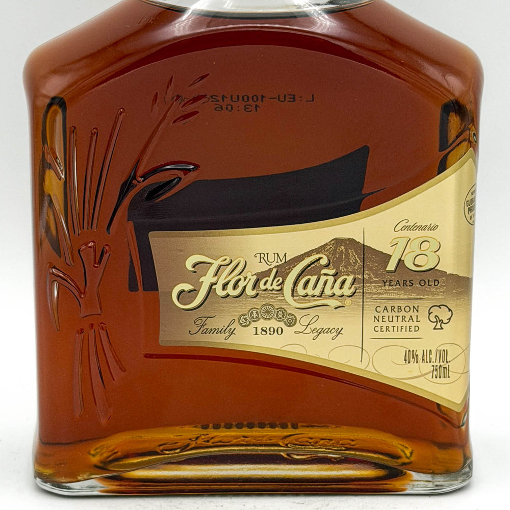 A close-up of a bottle of Flor de Cana 18 Years Old rum, showing the amber liquid and the cream and gold label with black and gold text.