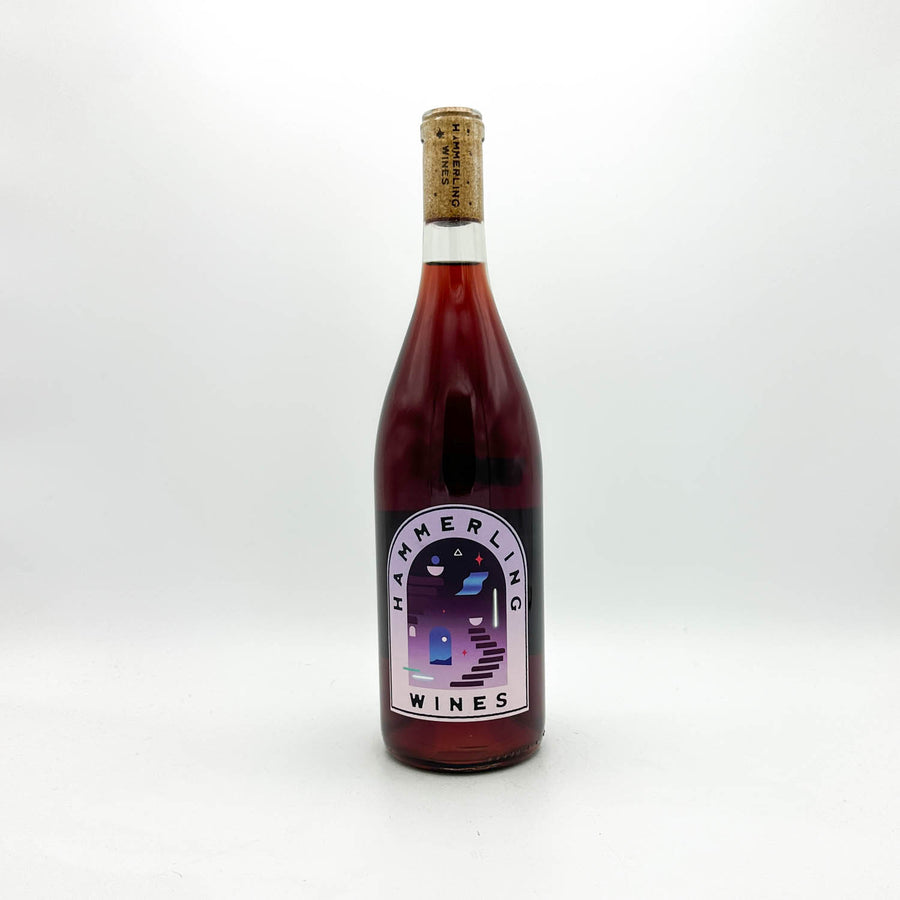 A bottle of Hammerling Wines red wine with a dark red liquid, a cork stopper, and a white label with a purple and blue illustration, set against a plain white background.