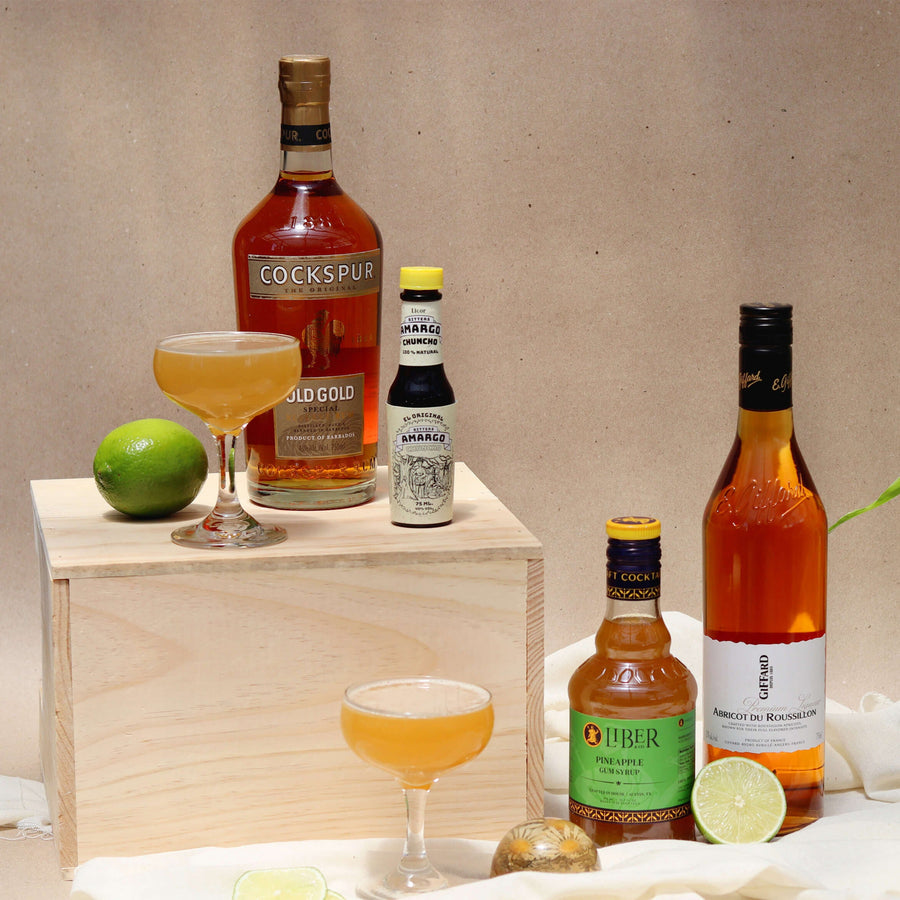 Bottles of alcohol and a cocktail on a wooden stand with a neutral background
