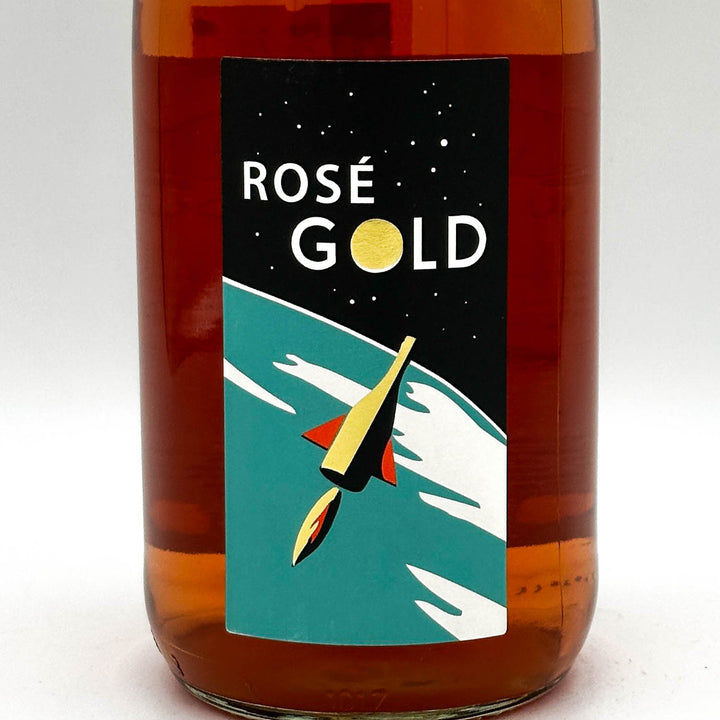 Bottle of Rosé Gold with a rocket illustration on a label against a white background
