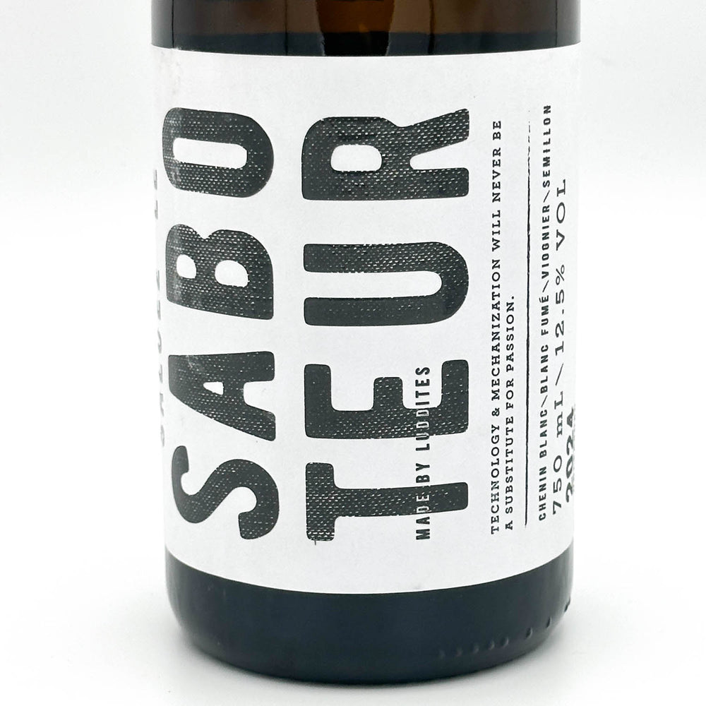 A dark brown glass bottle of Sabo Teur beer with a white label and a neck tag, photographed on a seamless white background.
