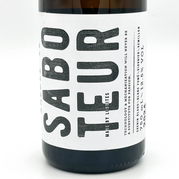 A dark brown glass bottle of Sabo Teur beer with a white label and a neck tag, photographed on a seamless white background.
