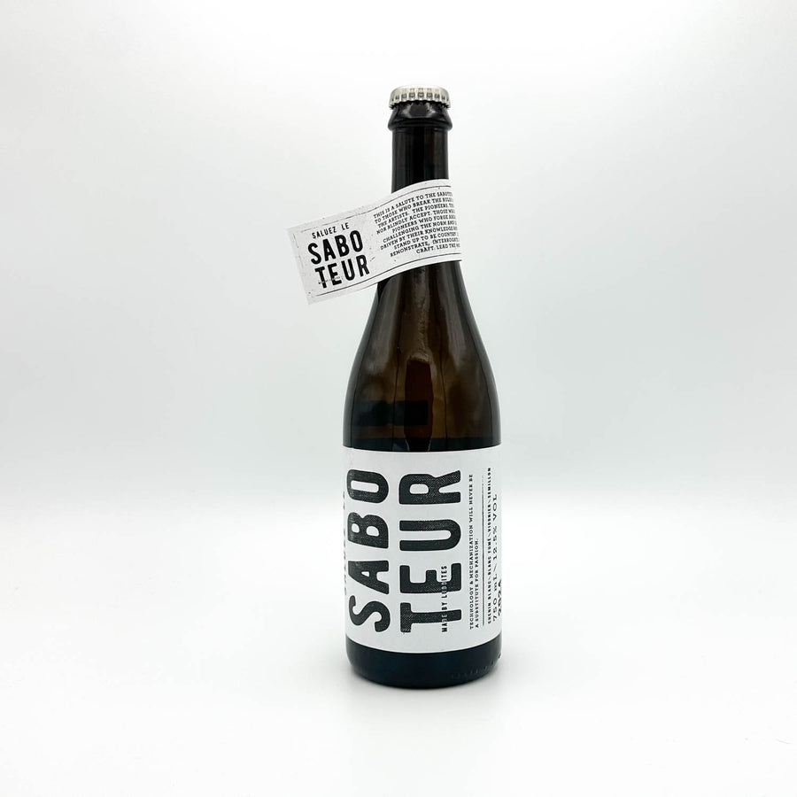 A dark brown glass bottle of Sabo Teur beer with a white label and a neck tag, photographed on a seamless white background.