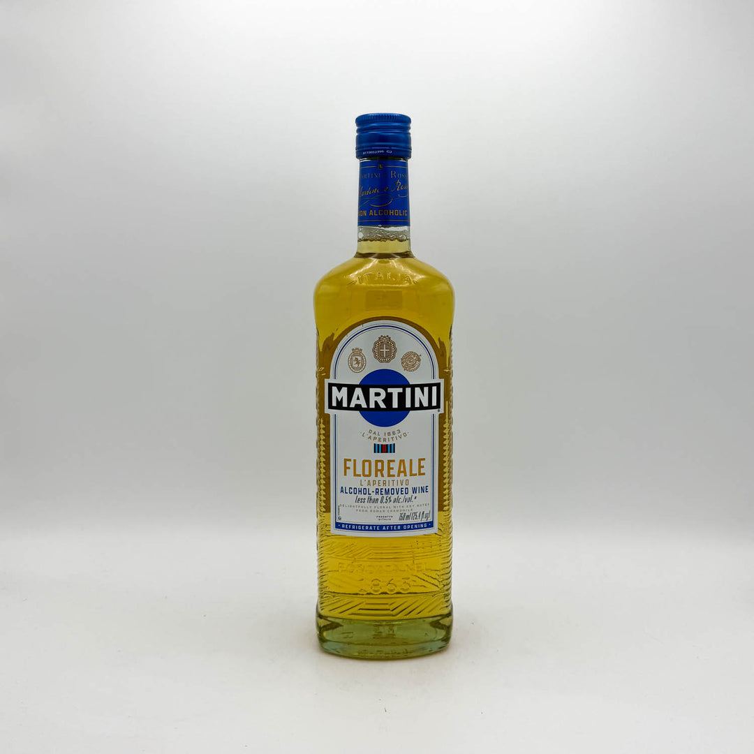 A bottle of Martini Florence non-alcoholic aperitif drink with golden yellow liquid inside, a blue cap, and a white and blue label, set against a plain light gray background.