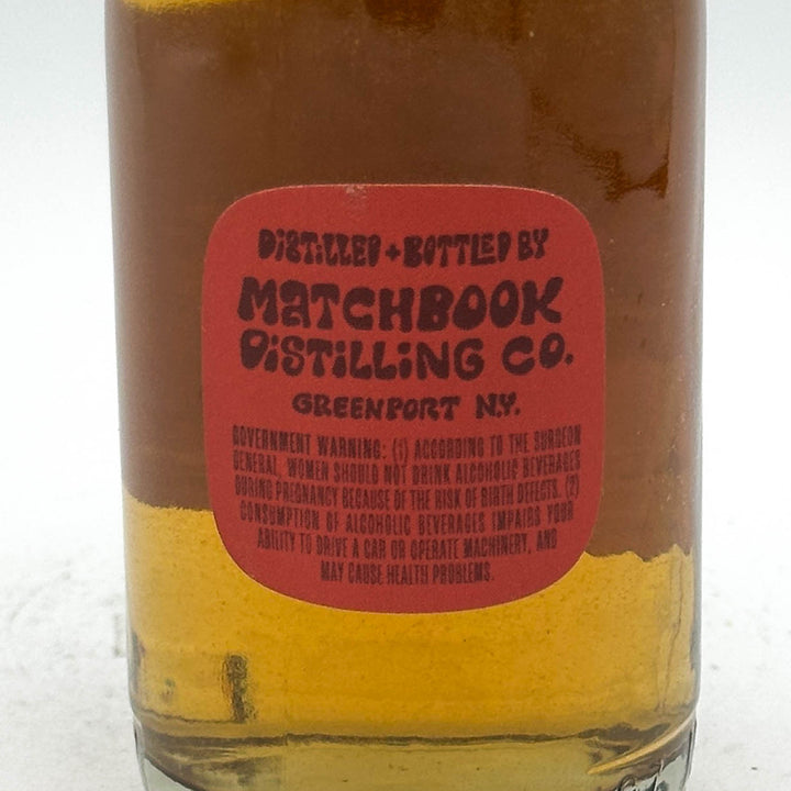 Bottle with a red label from Matchbook Distilling Co. on a white background