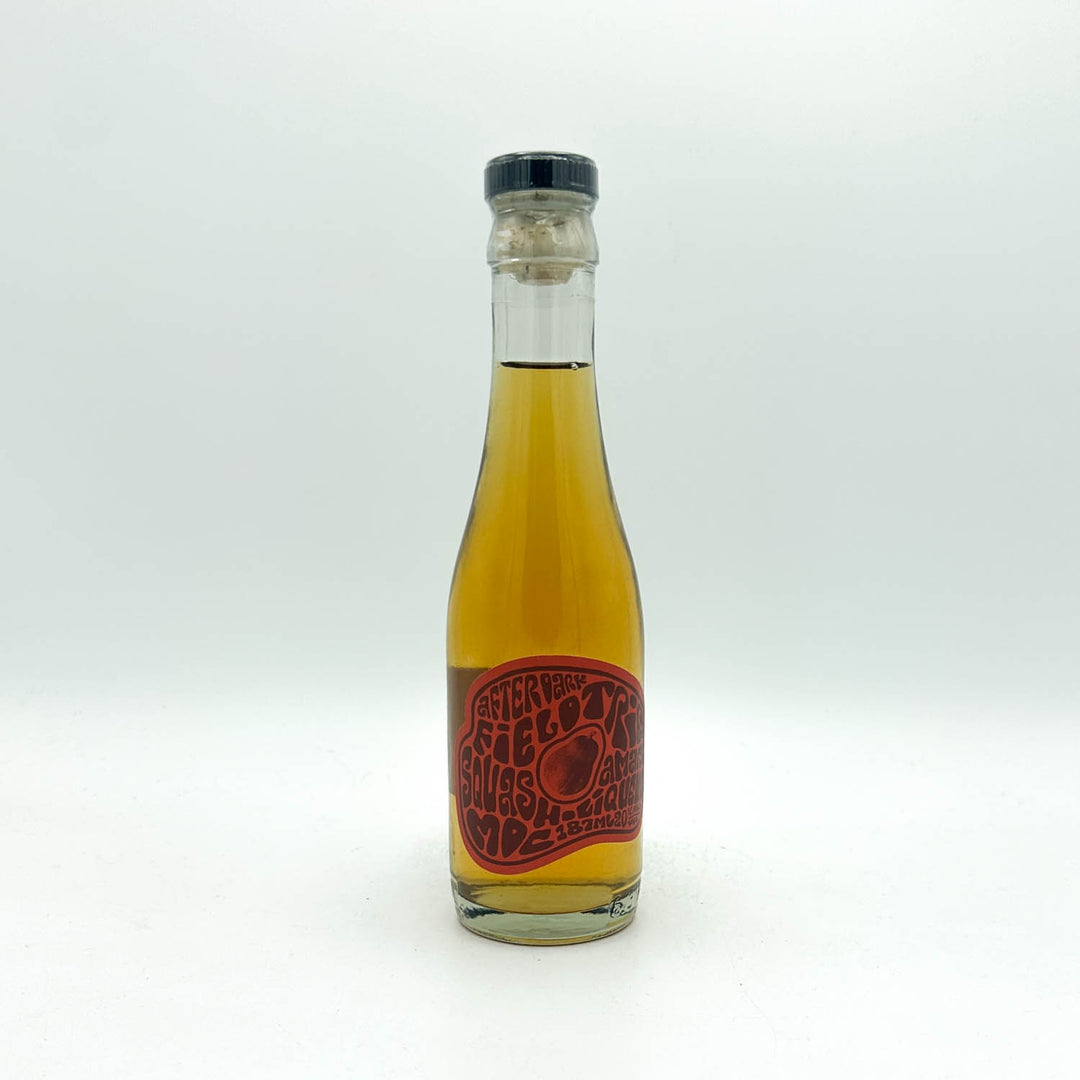Bottle of yellow liquid with a red label on a white background