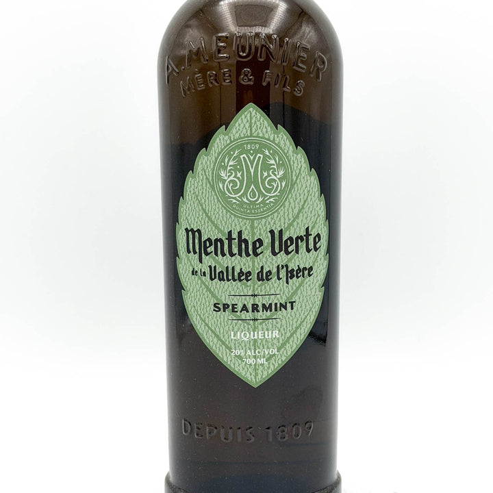 Bottle of Menthe Verte liqueur with a green label on a white background