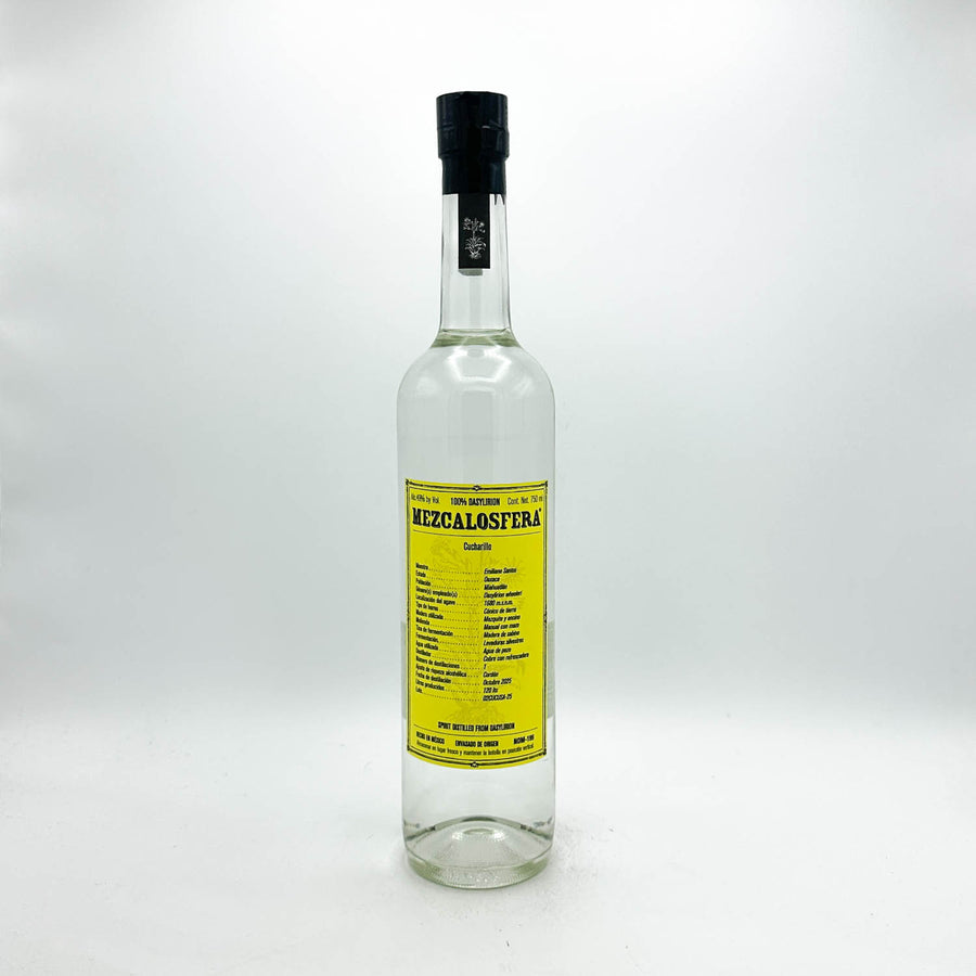 A clear glass bottle of Mezzalostera Mezzalastera liquor with a bright yellow label and a black screw cap, set against a plain light gray background.