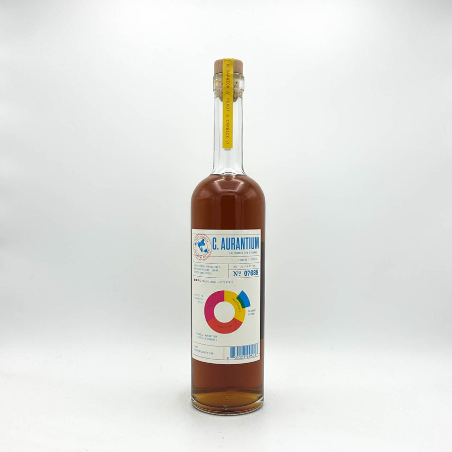 A clear glass bottle of C. Aurantium syrup with amber-brown liquid inside, a white label with blue and multicolor graphics, and a cork stopper with a yellow seal, photographed on a light gray background.