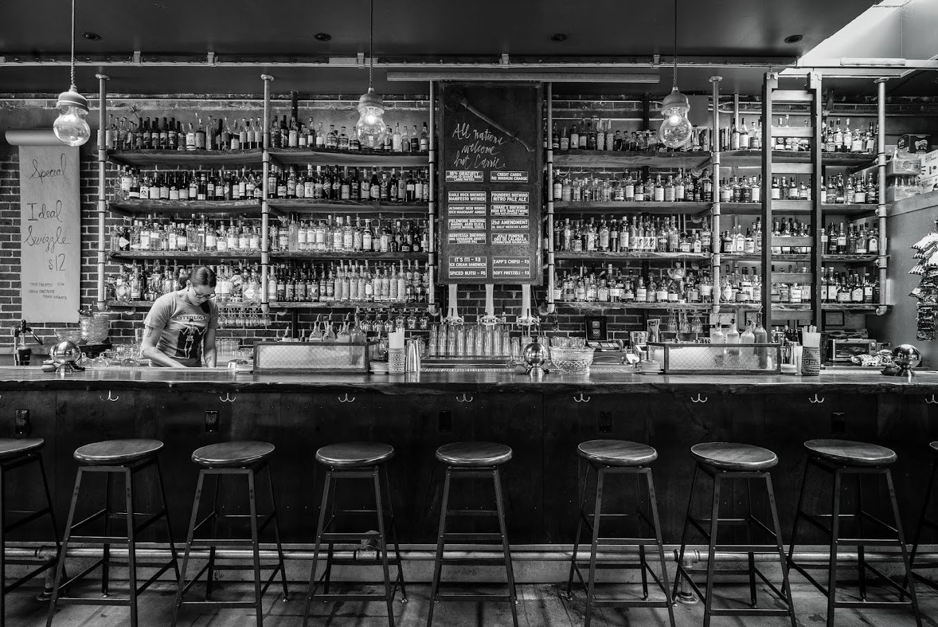 Black and white image of the Prizefighter bar with a bartender standing behind it