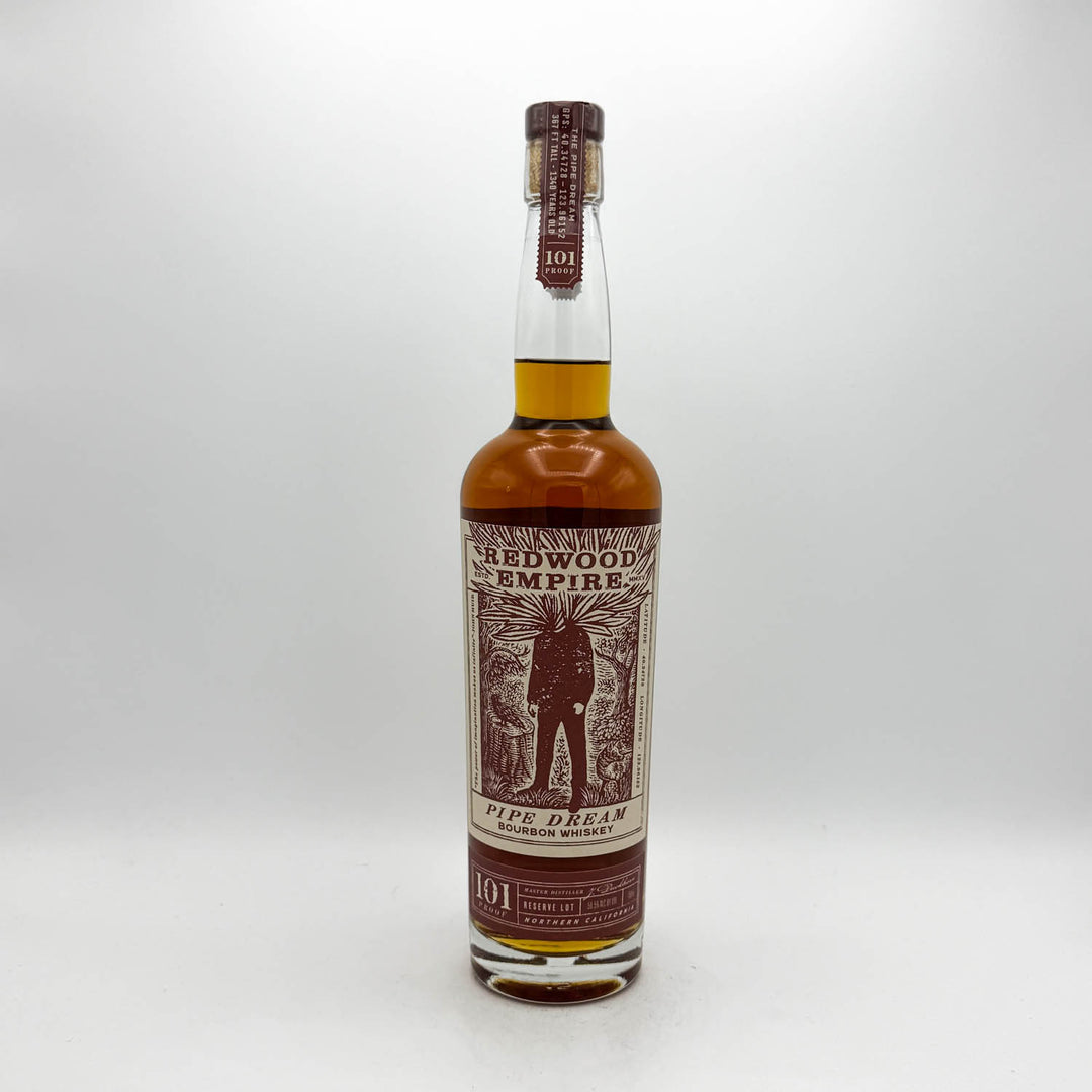 A bottle of 101 Redwood Empire Pipe Dream single malt whisky, featuring a brown and beige label with an illustration of a pipe player, set against a plain light gray background.