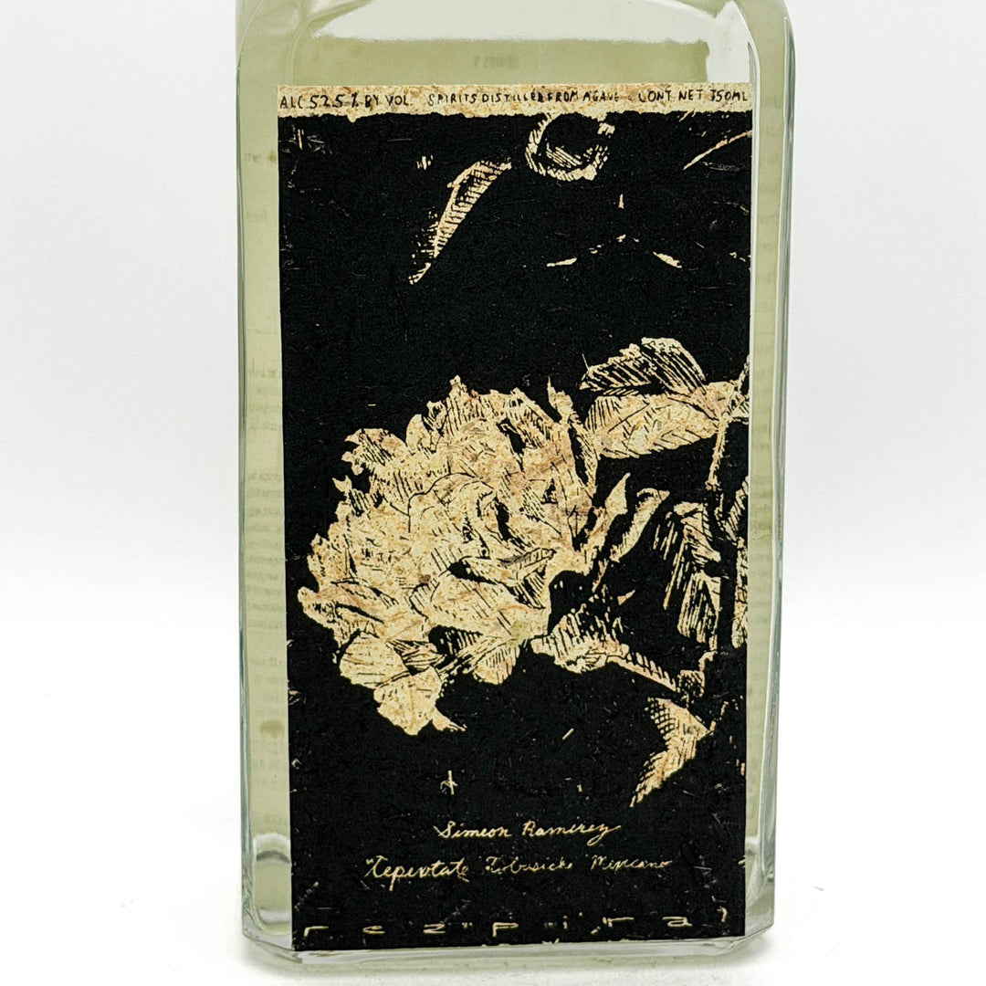 Glass bottle with black label featuring floral design and text