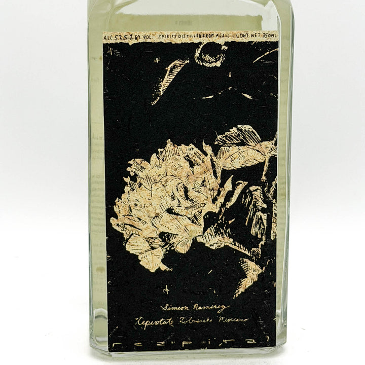 Glass bottle with black label featuring floral design and text