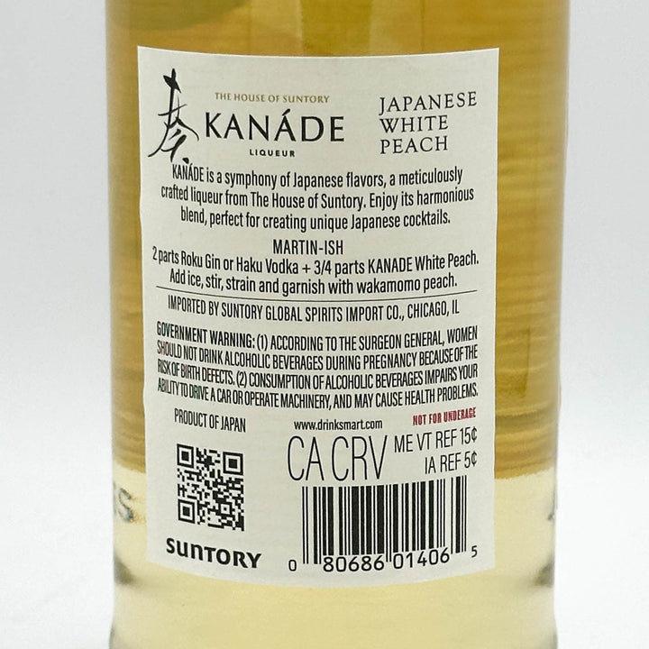Close-up of the back label of a Suntory Kanaōe Japanese White Peach liquor bottle, showing product information, barcode, QR code, and ingredients.