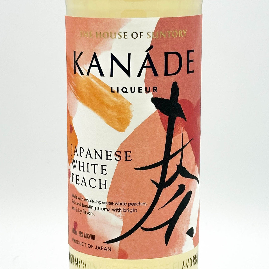 A bottle of Kanade Liqueur Japanese White Peach, featuring a peach and orange abstract label with black calligraphy and text, set against a plain white background.