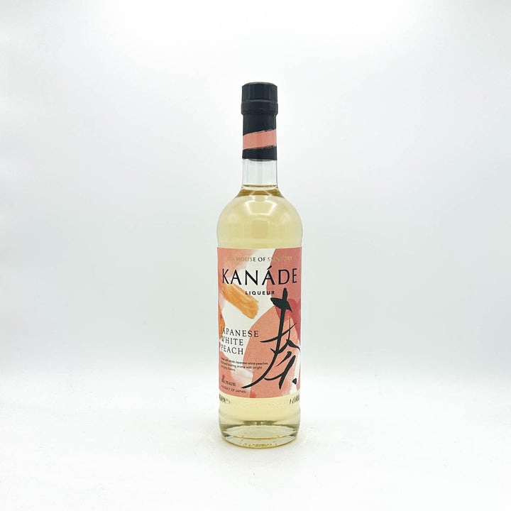 A bottle of Kanade Japanese White Peach syrup, featuring a clear glass bottle filled with pale yellow liquid, a pink and orange label with black calligraphy, and a black cap, set against a plain white background.
