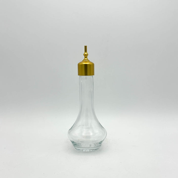 Clear glass bottle with a gold cap on a light gray background