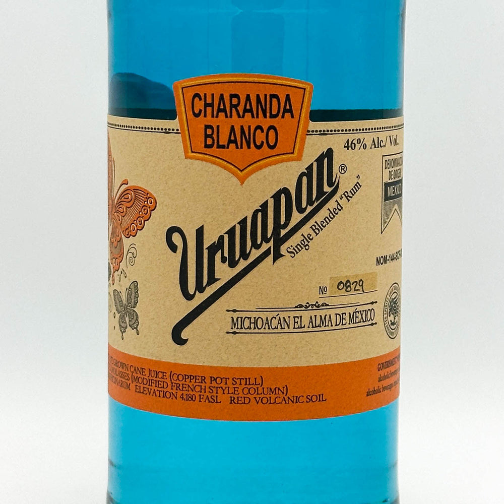 Bottle of Uruapan Charanda Blanco Rum with a blue label on a white background