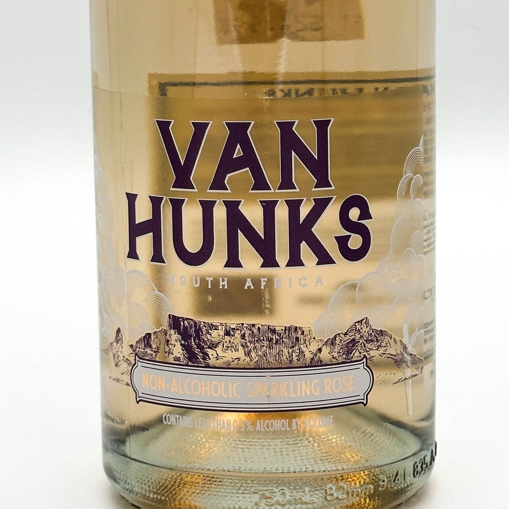 A bottle of Van Hunks sparkling wine with a light pinkish liquid, featuring a beige label with purple text and a cork closure, set against a plain light gray background.