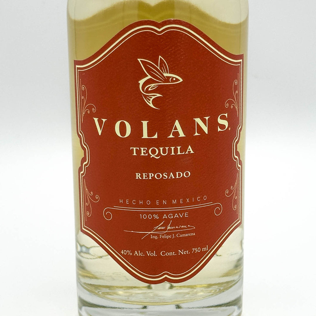 A bottle of Volans Tequila Reposado, showing the amber-brown liquid and a prominent reddish-brown label with gold lettering.