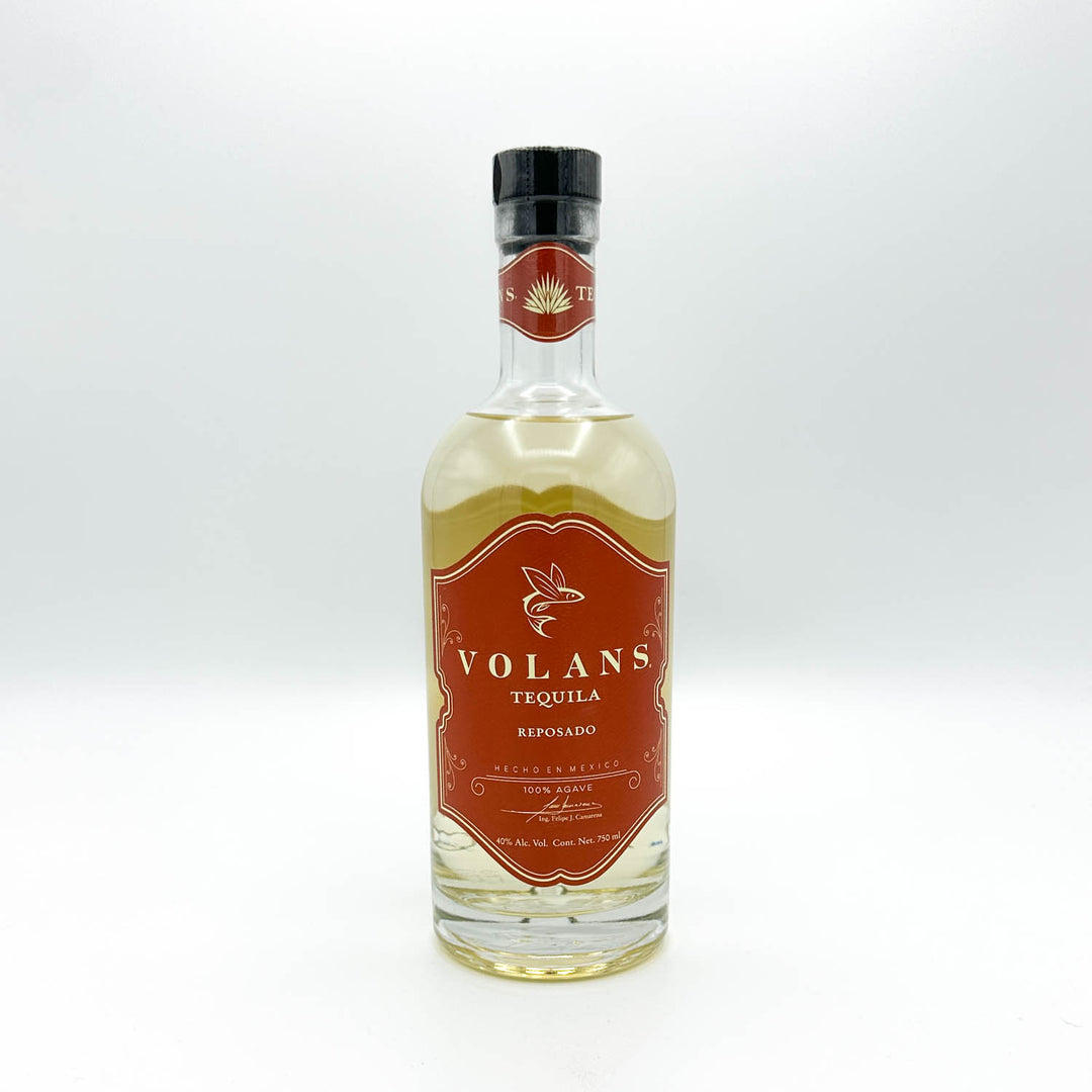 A bottle of Volans Tequila Reposado, showing the amber-brown liquid and a prominent reddish-brown label with gold lettering.