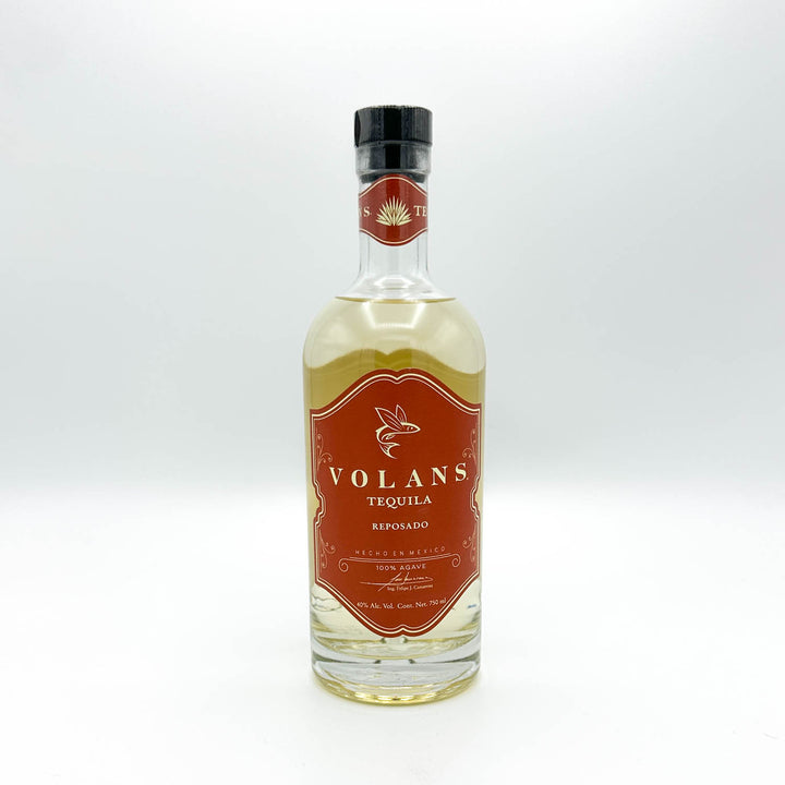A bottle of Volans Tequila Reposado, showing the amber-brown liquid and a prominent reddish-brown label with gold lettering.