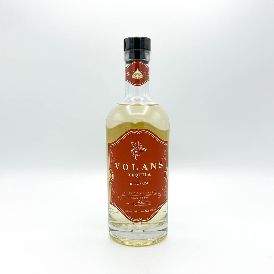 A bottle of Volans Tequila Reposado, showing the amber-brown liquid and a prominent reddish-brown label with gold lettering.