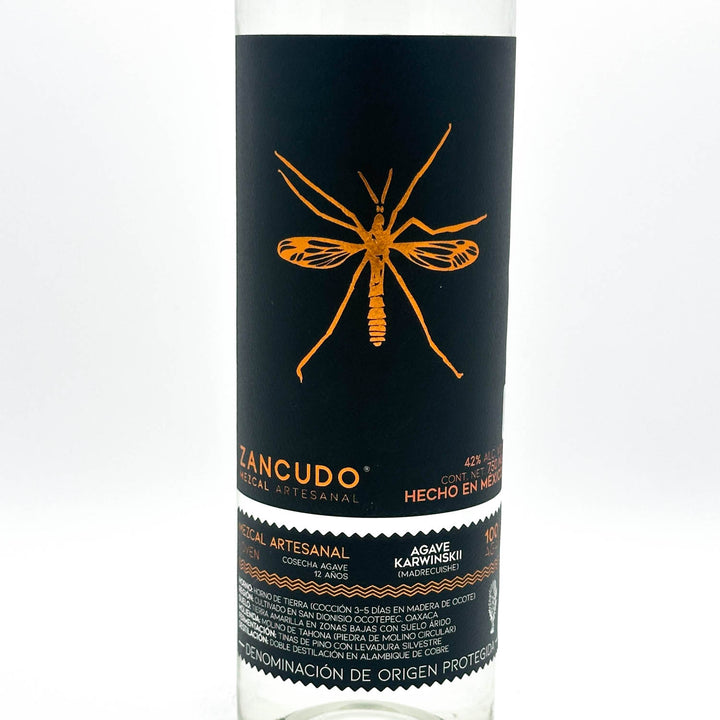 Bottle of Zancudo tequila with a black label featuring an orange mosquito illustration on a white background.