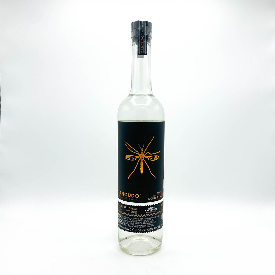 Clear bottle with black label featuring a gold insect design on a white background